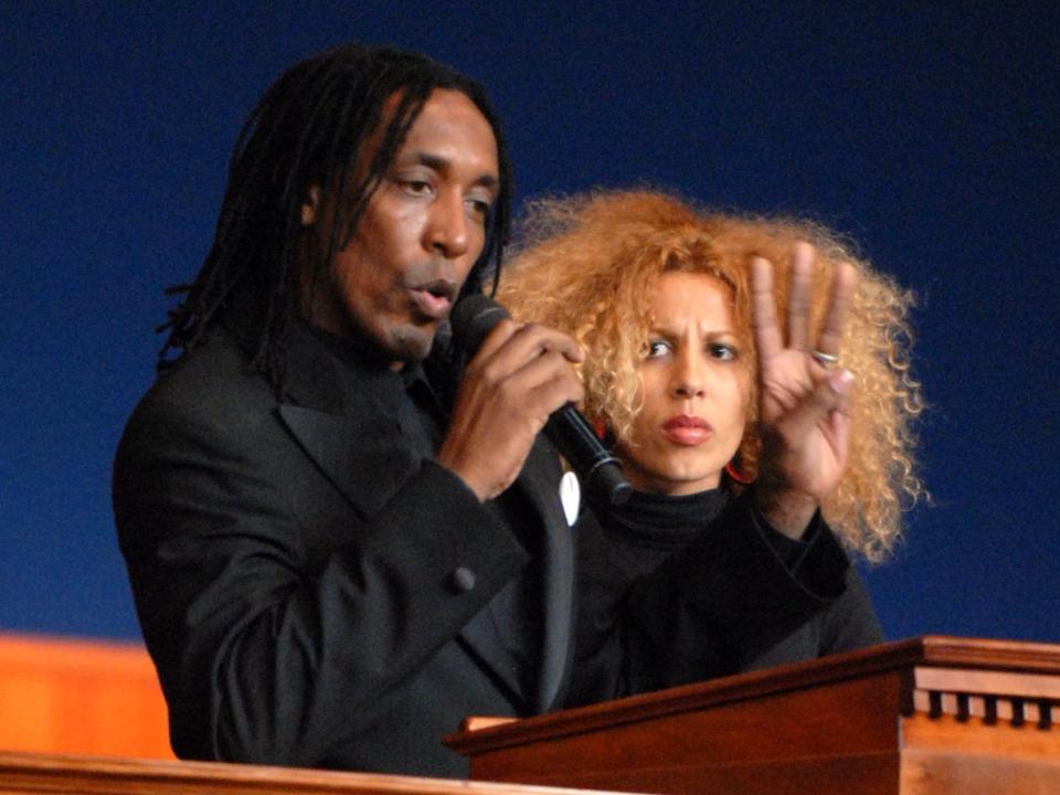 Ronald Turner speaking into a microphone with his hand raised toward a podium.