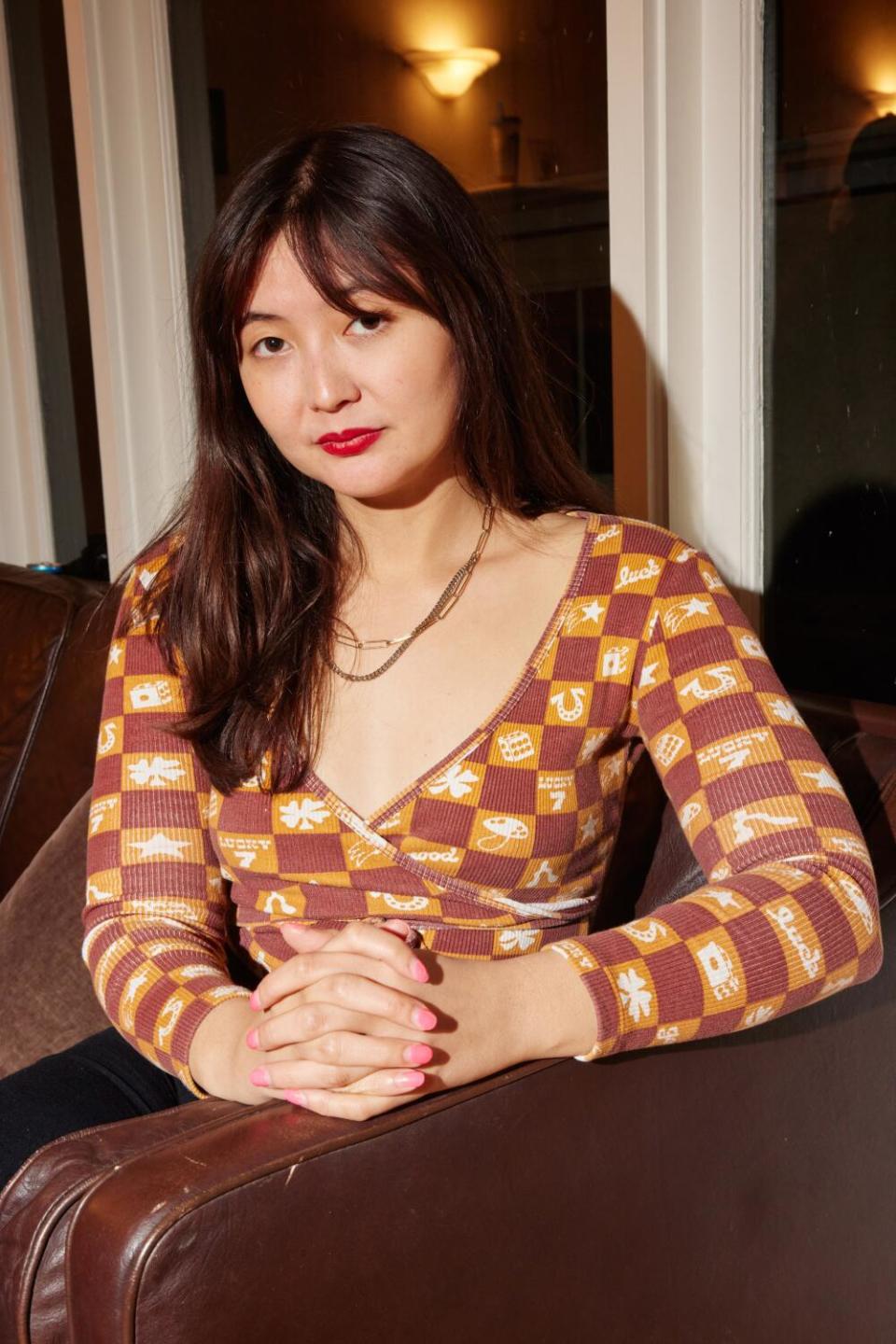 A woman with long hair in a long-sleeved, lowcut checkerboard top