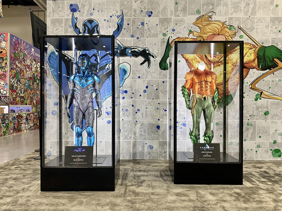 Costumes for Blue Beetle and Aquaman and the Lost Kingdom, and worn by actors Xolo Marduena and Jason Momoa respectively, stand tall at the DC booth.