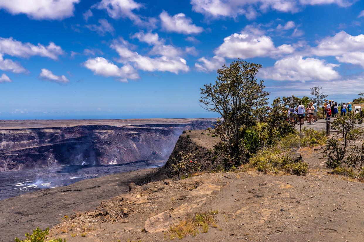 Visitors watch steam and gas rise from Halema'uma'u Crater at the summit of Kīlauea volcano after its June 2023 eruption.