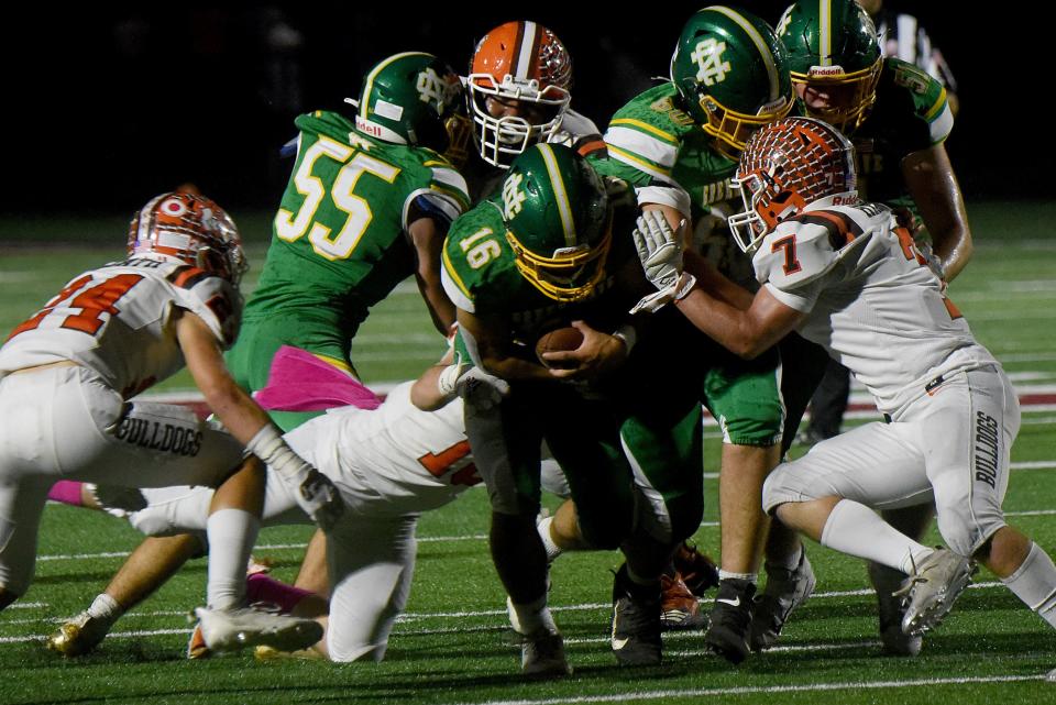 Heath's Connor Corbett (7) and Paul Gould (24) move in to tackle Newark Catholic's Mason Hackett during the Bulldogs' 28-21 win in 2021.