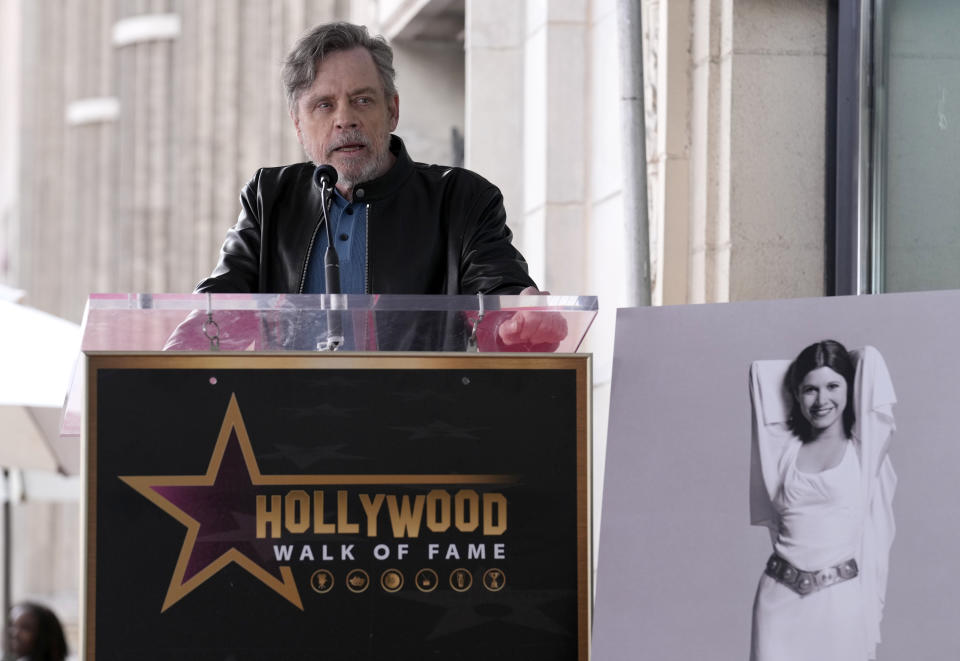 Mark Hamill habla durante una ceremonia en honor a la fallecida actriz Carrie Fisher, en una fotografía a la derecha, durante una ceremonia para develar su estrella póstuma en el Paseo de la Fama de Hollywood en Los Ángeles el jueves 4 de mayo de 2023. La fecha se conoce también como Día de Star Wars, en homenaje a las películas de "Star Wars" en las que Fisher interpretó a la Princesa Leia. (Foto AP/Chris Pizzello)