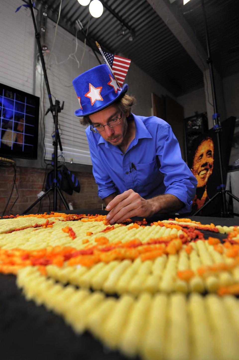 IMAGE DISTRIBUTED FOR CHEETOS - Artist Jason Baalman puts the finishing touches on a Cheetos portrait of former Gov. Mitt Romney Tuesday, Oct. 2, 2012, in Baalman’s Colorado Springs, Colo., studio. Today, the Cheetos brand unveiled a new electoral polling model with the unveiling of 3 feet by 4 feet one-of-a-kind Cheetos portraits of the Democratic and Republican presidential nominees – President Barack Obama and former Gov. Mitt Romney. Debuting on Facebook today at 11 a.m. CT, fans are encouraged to vote for their candidate’s portrait – made entirely of more than 2,000 individual Cheetos cheese snacks – for a chance to win the actual portrait. (Photo by Jack Dempsey/Invision for Cheetos/AP Images)