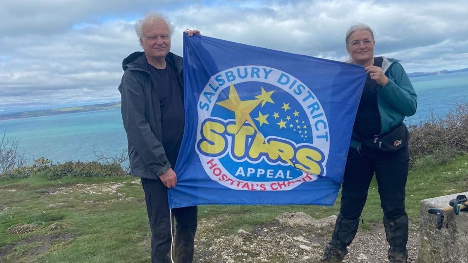 Dr Helena McKeown and Peter Ewing holding a stars appeal flag on top of a cliff