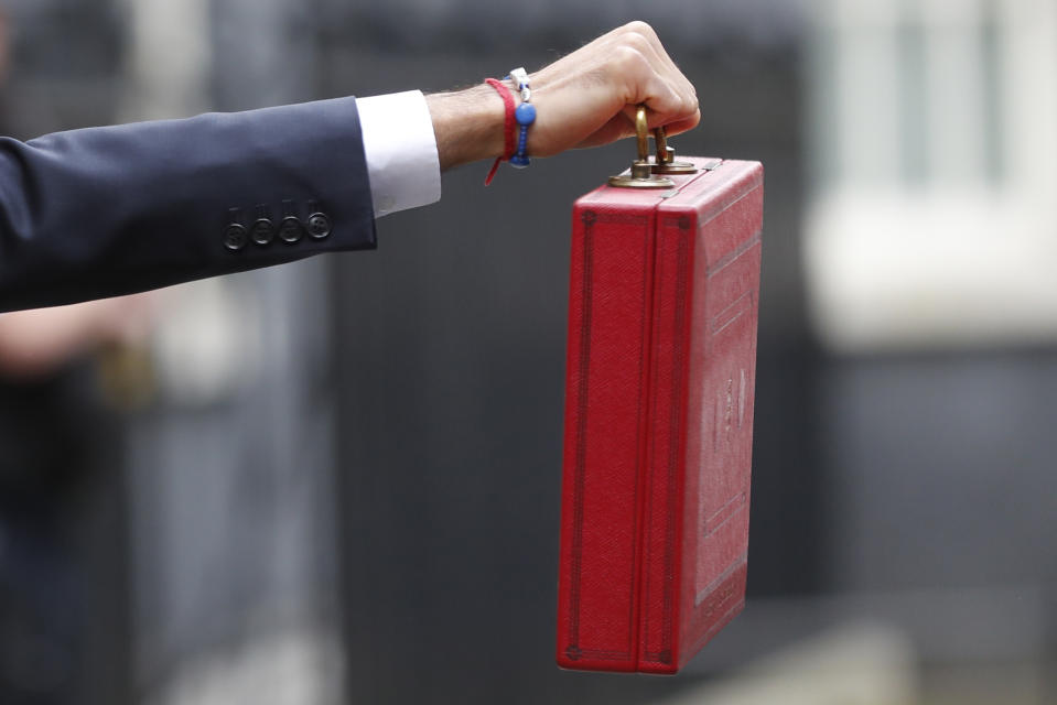 Britain's Chancellor of the Exchequer Rishi Sunak stands outside No 11 Downing Street and holds up the traditional red box that contains the budget speech for the media, he will then leave to make budget speech to House of Commons, London, Wednesday, March 11, 2020. Britain's Chancellor of the Exchequer Rishi Sunak will announce the first budget since Britain left the European Union. (AP Photo/Frank Augstein)