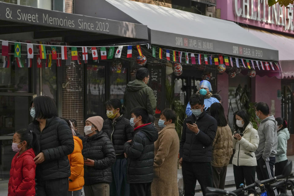 FILE - Residents wearing face stand in line for their routine COVID-19 tests near shuttered restaurants and shops as part of COVID-19 controls in Beijing, Nov. 22, 2022. (AP Photo/Andy Wong, File)