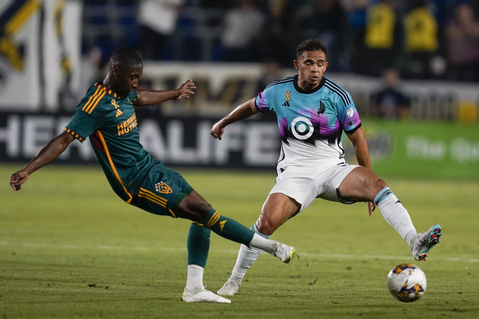 Minnesota United midfielder Hassani Dotson, right, lunges as LA Galaxy defender Kelvin Leerdam clears the ball during the first half of an MLS soccer match Wednesday, Sept. 20, 2023, in Carson, Calif. (AP Photo/Ryan Sun)