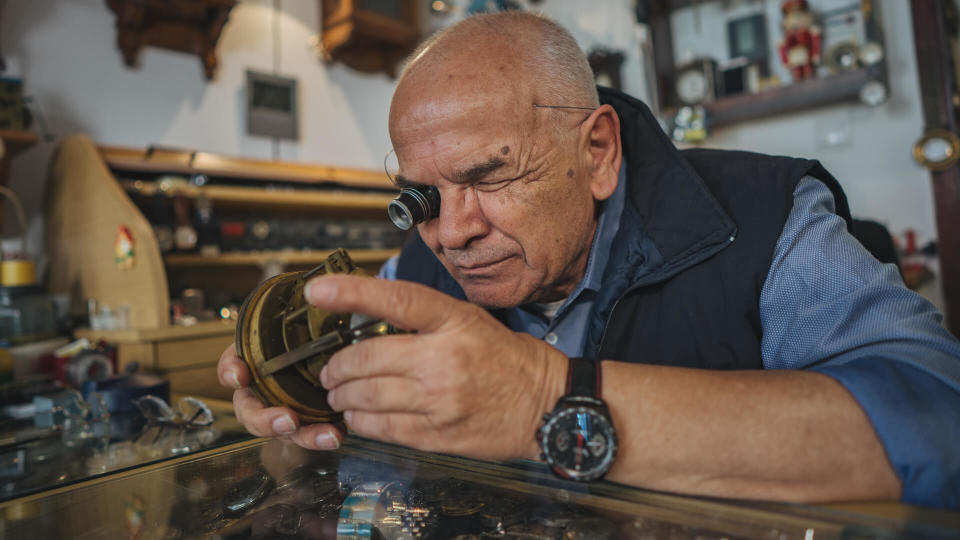 Senior watchmaker repairing old clock in his workshop.