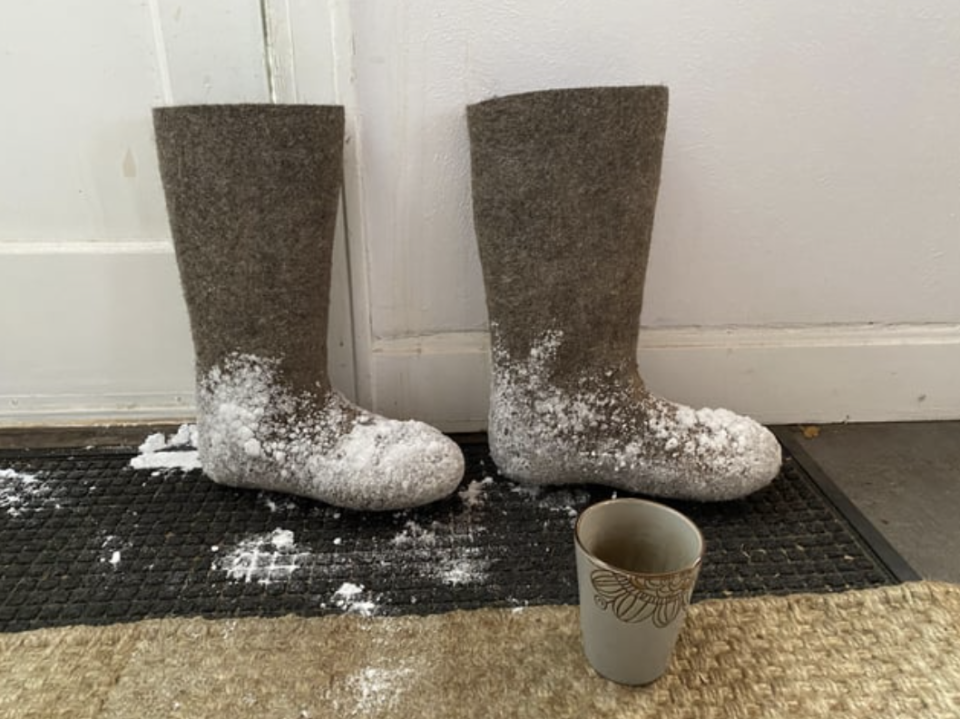 Calf-high boots with snow on them on a mat