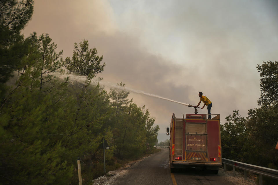 Firefighters work in the smoke-engulfed Mazi area as wildfires rolled down the hill toward the seashore, forcing people to be evacuated, in Bodrum, Mugla, Turkey, Sunday, Aug. 1, 2021. More than 100 wildfires have been brought under control in Turkey, according to officials. The forestry minister tweeted that five fires are continuing in the tourist destinations of Antalya and Mugla.(AP Photo/Emre Tazegul)