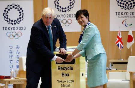 Britain's Foreign Secretary Boris Johnson (L), flanked by Tokyo Governor Yuriko Koike, feeds a smartphone into a box collecting old mobile phones from Tokyo residents, which will be recycled into medals for the 2020 Tokyo Olympics and Paralympics, during their meeting at Tokyo Metropolitan Government buildingin Tokyo, Japan July 21, 2017. REUTERS/Issei Kato