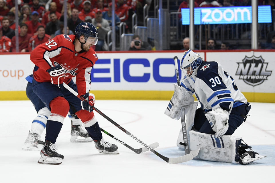 Winnipeg Jets goaltender Laurent Brossoit (30) stops the puck in front of Washington Capitals center Evgeny Kuznetsov (92), of Russia, during the second period of an NHL hockey game Tuesday, Feb. 25, 2020, in Washington. (AP Photo/Nick Wass)