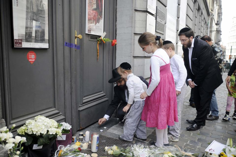 A family lights candles at the Jewish Museum, site of a shooting in central Brussels