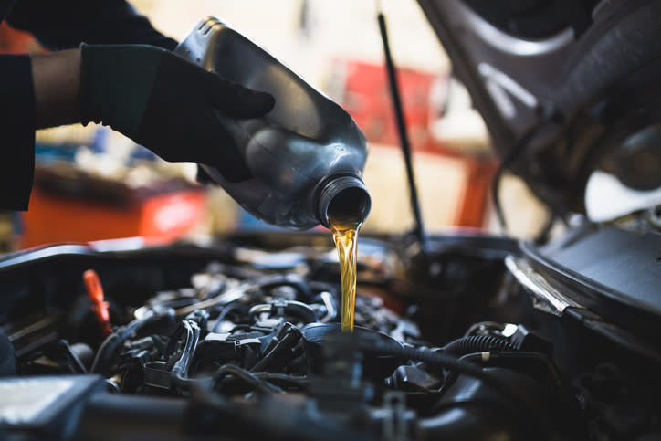 A mechanic pouring oil into an engine.