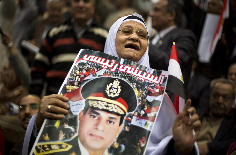 An Egyptian woman holds a poster of Egypt's Defense Minister, Gen. Abdel-Fattah el-Sissi, with Arabic writing that reads, "el-Sissi is my president," and a national flag during a rally in support of el-Sissi, in Cairo, Egypt, Tuesday, Jan. 21, 2014. Supporters of the powerful army chief and defense minister urged Egyptians on Tuesday to turn the third anniversary to 2011 uprising that toppled longtime autocratic president Hosni Mubarak, to a show of gratitude to the general for ousting Islamist president, calling on him to contest elections. (AP Photo/Khalil Hamra)