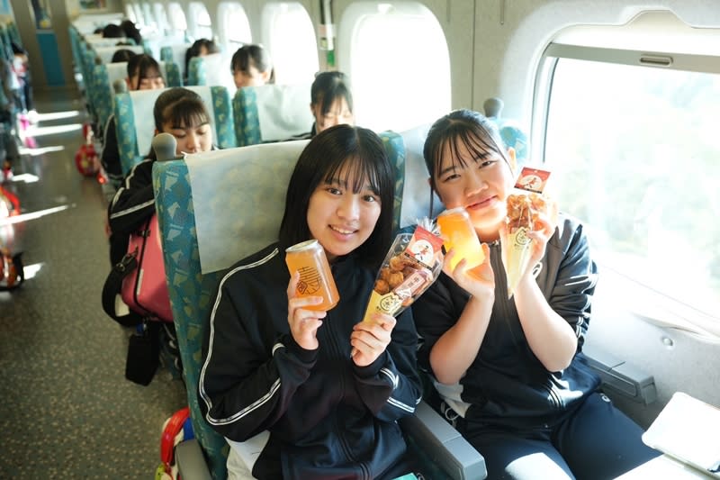有「橘色惡魔」之稱的日本京都橘高校吹奏樂部10日下午將在高雄時代大道演出，高市府特別送上甜筒小泡芙及「橘色特調」氣泡水，讓學生們在高鐵上享用。（圖／高雄市政府提供）