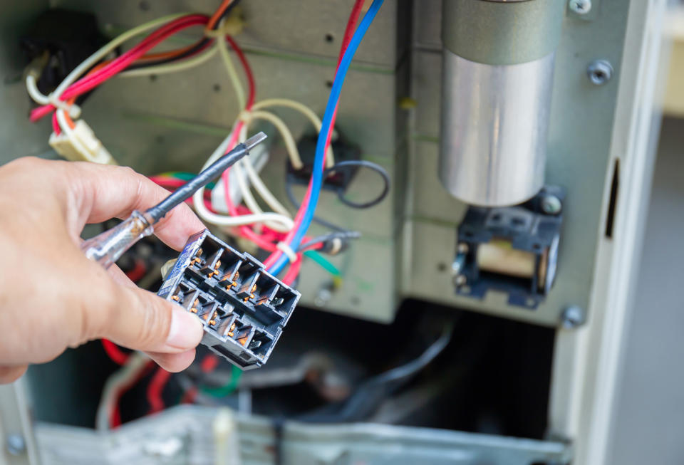 Professional checking various wires attached to an HVAC system