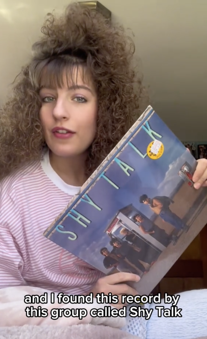 Woman showing a Shy Talk record album and speaking about the group Shy Talk