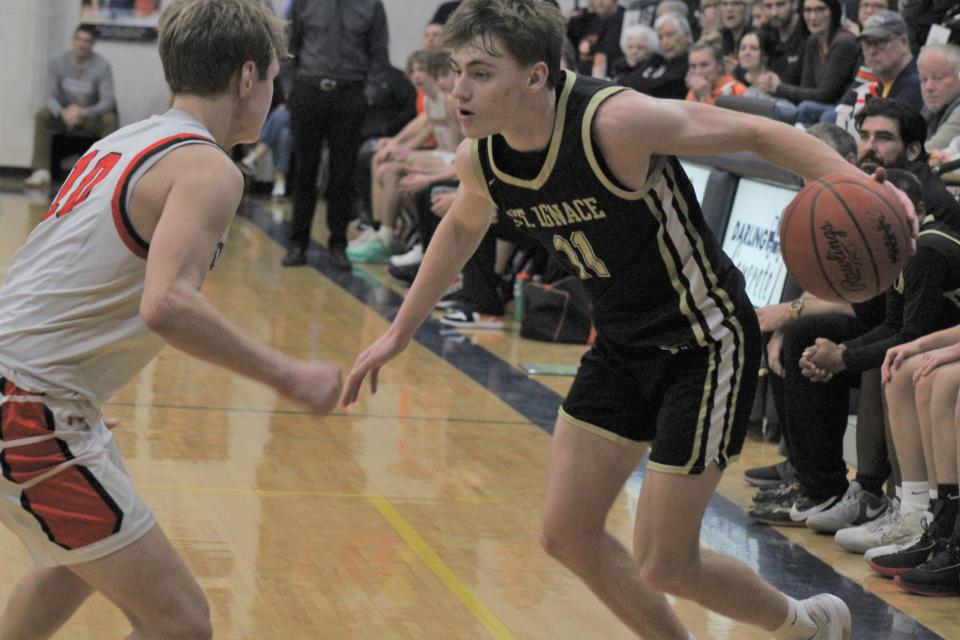 St. Ignace senior guard Jonny Ingalls (right) attempts to drive past Munising's Garrett Martin during the second half of Thursday's MHSAA Division 4 regional boys basketball final at Sault Ste. Marie.