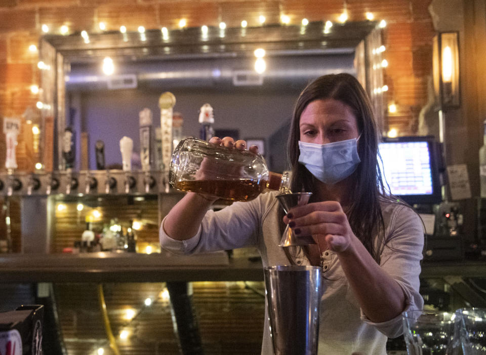 Bartender Kellie Mottiqua prepares drinks, Monday, Nov. 23, 2020, at Bridgetown Taphouse in Ambridge, Penn. Earlier in the day, with the state's surge in new COVID-19 cases, hospitalizations and deaths, Gov. Tom Wolf and Health Secretary Rachel Levine announced a series of orders and advisories, including a stay-at-home advisory, and an order suspending all alcohol sales in bars, restaurants or catered events during the night before Thanksgiving. (Emily Matthews/Pittsburgh Post-Gazette via AP)