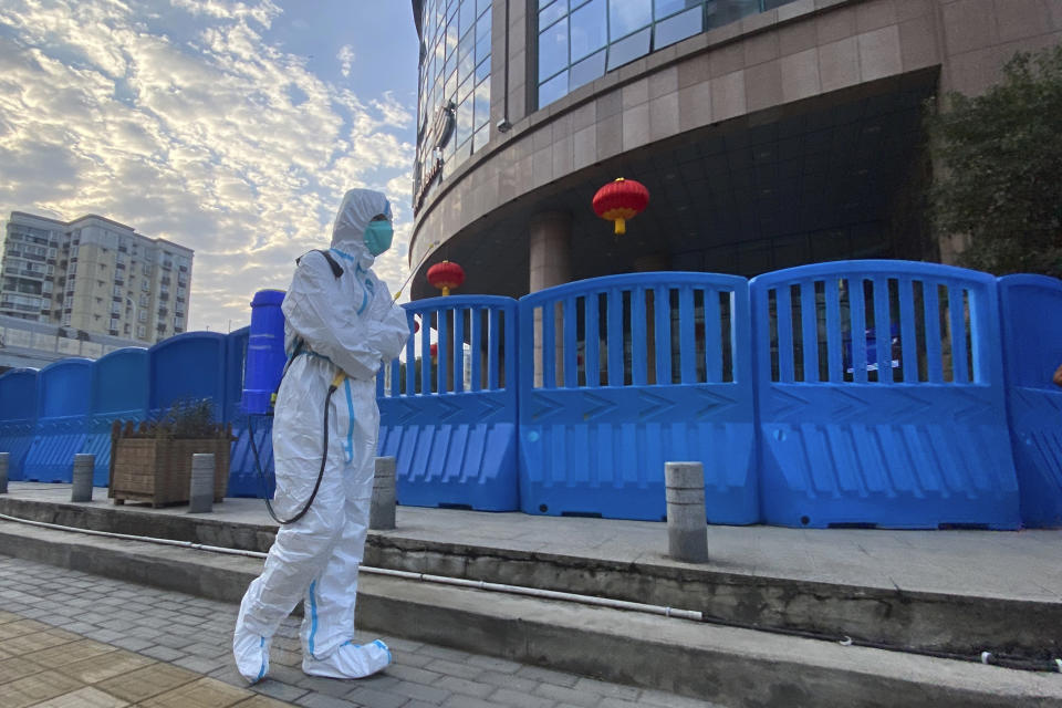 FILE - In this Feb. 6, 2021, file a worker in protectively overalls and carrying disinfecting equipment walks outside the Wuhan Central Hospital where Li Wenliang, the whistleblower doctor who sounded the alarm and was reprimanded by local police for it in the early days of Wuhan's pandemic, worked in Wuhan in central China. U.S. intelligence agencies remain divided on the origins of the coronavirus but believe China's leaders did not know about the virus before the start of the global pandemic, according to results released Friday, Aug. 27, of a review ordered by President Joe Biden. (AP Photo/Ng Han Guan, File)