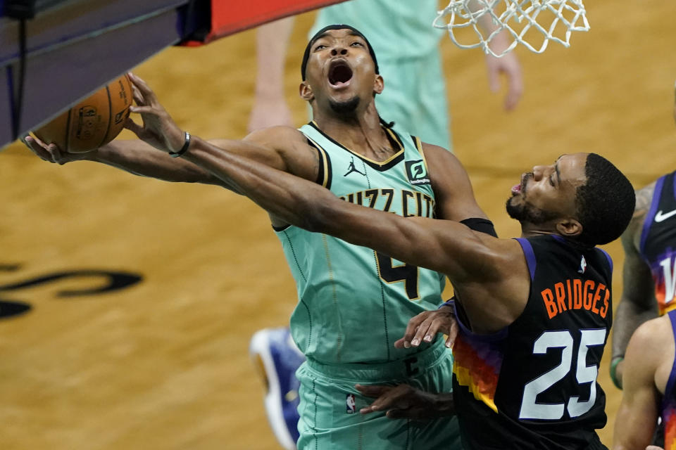 Phoenix Suns forward Mikal Bridges blocks a shot by Charlotte Hornets guard Devonte' Graham during the first half of an NBA basketball game on Sunday, March 28, 2021, in Charlotte, N.C. (AP Photo/Chris Carlson)