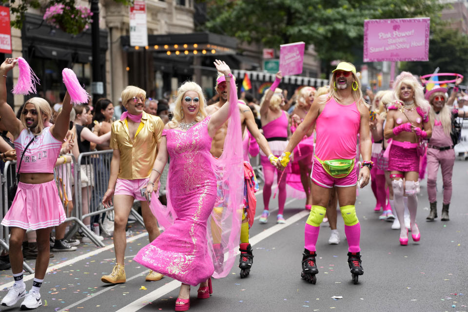 FILE - Parade-goers promoting the upcoming "Barbie" movie walk in the NYC Pride March, June 25, 2023, in New York. With the Friday, July 21, release of the "Barbie movie" starring Margot Robbie, the color “Barbie Pink” has been thrown into the spotlight on social media and the world of fashion. (Photo by Charles Sykes/Invision/AP, File)