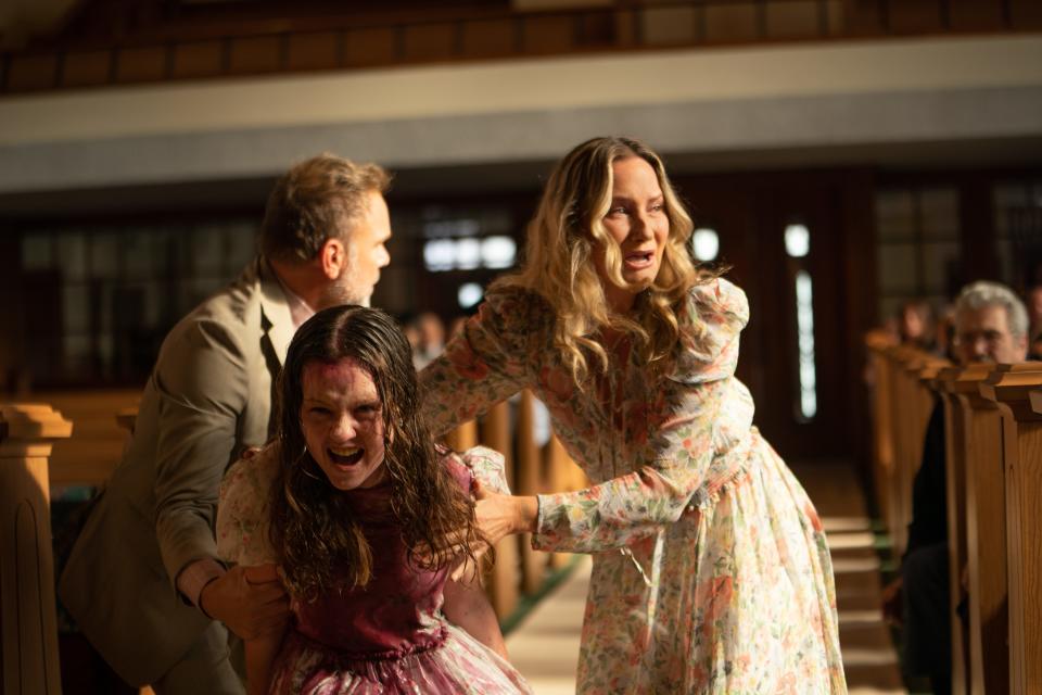 Katherine (Olivia O’Neill, center) has a violent episode in church and her parents Tony (Norbert Leo Butz) and Miranda (Jennifer Nettles) try to fix the situation in" The Exorcist: Believer."