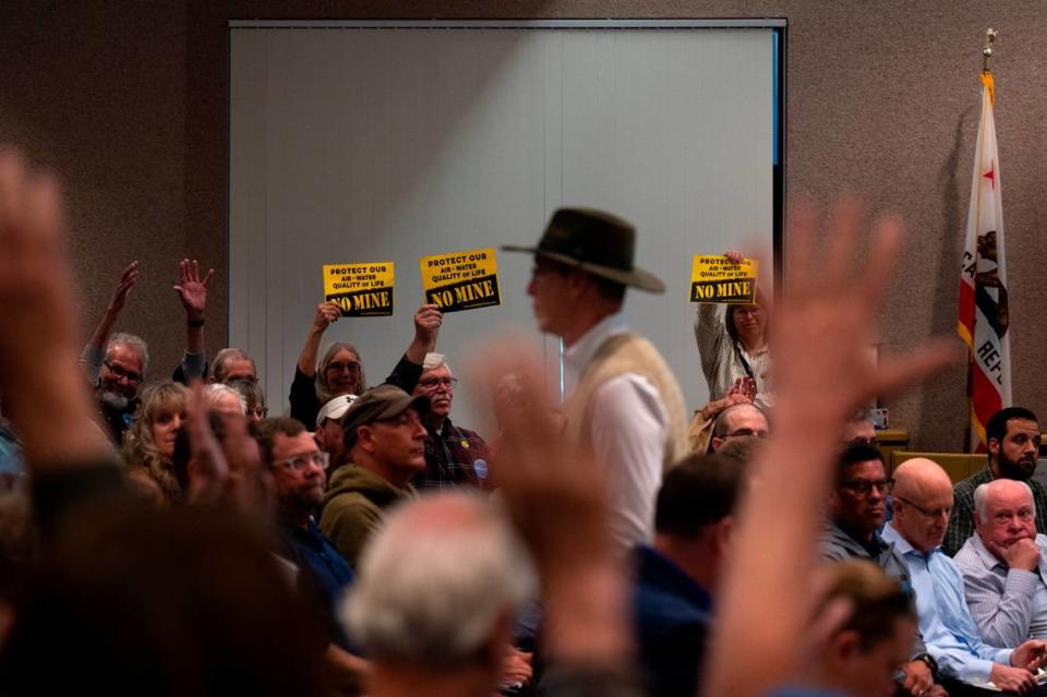 Members of the public hold up “no mine” signs, while others wave their hands in the air in silent applause, as a man who spoke against the Idaho-Maryland Mine during public comment walks back to his seat on May 11 during the second day of the Nevada County planning commission hearings on the project. The commission later voted unanimously against the mine. 
