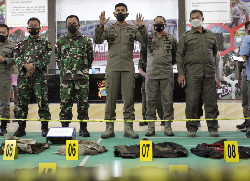 Central Sulawesi Police Chief Rudi Sufariadi, center, speaks to the media as the items confiscated from Ali Kalora and Jaka Ramadan, two militants who were killed during shootout with security forces, are displayed for the media during a press conference at the Parigi Moutong Police Station in Parigi Moutong district, Central Sulawesi, Indonesia, Sunday, Sept. 19, 2021. Indonesia's most wanted militant with ties to the Islamic State group was killed Saturday in a shootout with security forces, the Indonesian military said, in a sweeping counterterrorism campaign against extremists in the remote mountain jungles. (AP Photo/Josua Marunduh)