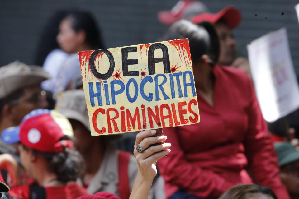 A supporter of Venezuela's president Nicolas Maduro, holds a sign that reads in Spanish "OAS Hypocrites, Criminals" during a government rally in Caracas, Venezuela, Saturday, April 27, 2019. The Trump administration has added Venezuelan Foreign Minister Jorge Arreaza to a Treasury Department sanctions target list as it increases pressure on embattled President Nicolas Maduro. (AP Photo/Ariana Cubillos)