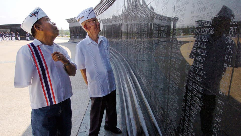 Disabled Filipino World War II veteran and death march survivor Manuel Abrazado, 80, (L) and his comrade Emilio Aquino, 86, (R) look at the names of their comrades at the Capas National Shrine in northern Tarlac province on April 6, 2004 during a memorial day marking the fall of Bataan. - Romeo Gacad/AFP/Getty Images