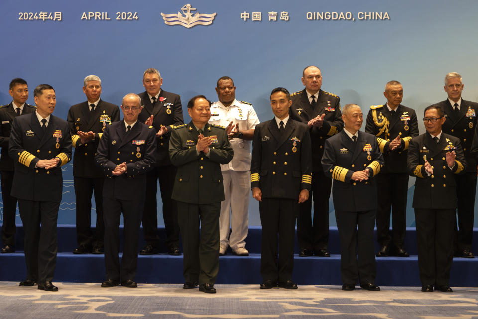 Zhang Youxia, center left in front, vice chairman of the CPC Central Military Commission, applauds after a group photo with attendees including Steve Koehler, right, commander of the U.S. Pacific Fleet, nd Alexander Moiseyev, fifth right, Russia's chief of Navy, before attending the Western Pacific Navy Symposium in Qingdao, eastern China's Shandong province on Monday, April 22, 2024. Zhang, China's second-ranking military leader under Xi Jinping, took a harsh line on regional territorial disputes on Monday, telling the international naval gathering in northeastern China that the country would strike back with force if its interests came under threat. (AP Photo/Ng Han Guan)