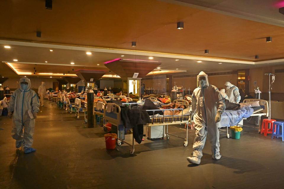 TOPSHOT - Health workers wearing personal protective equipment (PPE kit) attends to Covid-19 coronavirus positive patients inside a banquet hall temporarily converted into a covid care centre in New Delhi on April 29, 2021. (Photo by TAUSEEF MUSTAFA / AFP) (Photo by TAUSEEF MUSTAFA/AFP via Getty Images)