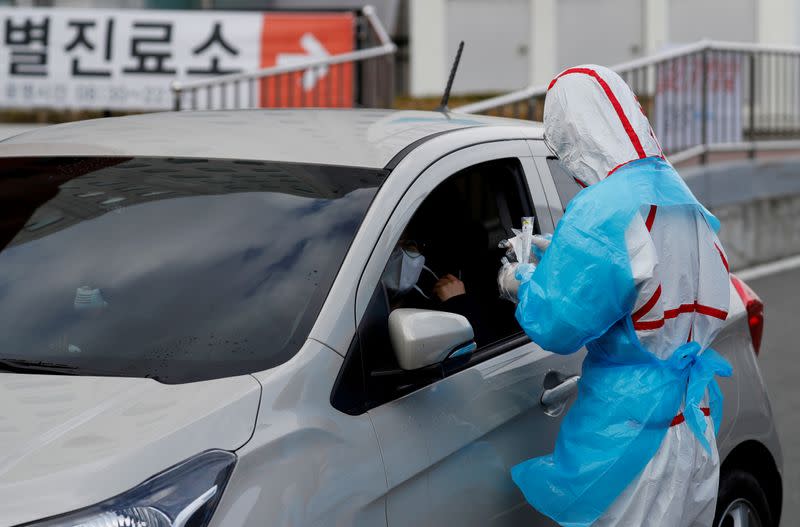 FILE PHOTO: A medical staff member in protective gear prepares to take samples from a visitor at a 'drive-thru' testing center for the novel coronavirus disease of COVID-19 in Yeungnam University Medical Center in Daegu