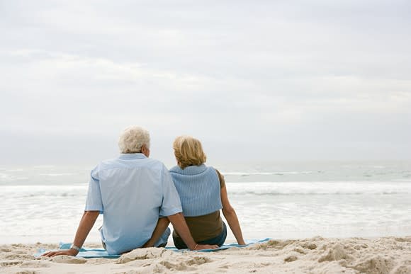Senior couple at the beach, facing the ocean