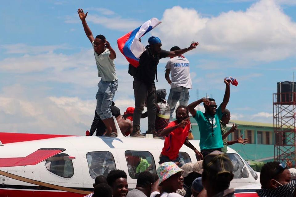 People gather on an airplane during a protest against insecurity and violence at the Antoine Simon Des Cayes airport in Les Cayes, Haiti, Tuesday, March 29, 2022. The protest coincides with the 35th anniversary of Haiti's 1987 Constitution and follows other protests and strikes in recent weeks in the middle of a spike in gang-related kidnappings.