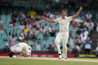 Australia's Pat Cummins, right, celebrates taking the wicket of England's Mark Wood, left, during the fifth day of their Ashes cricket test match in Sydney, Sunday, Jan. 9, 2022. (AP Photo/Rick Rycroft)