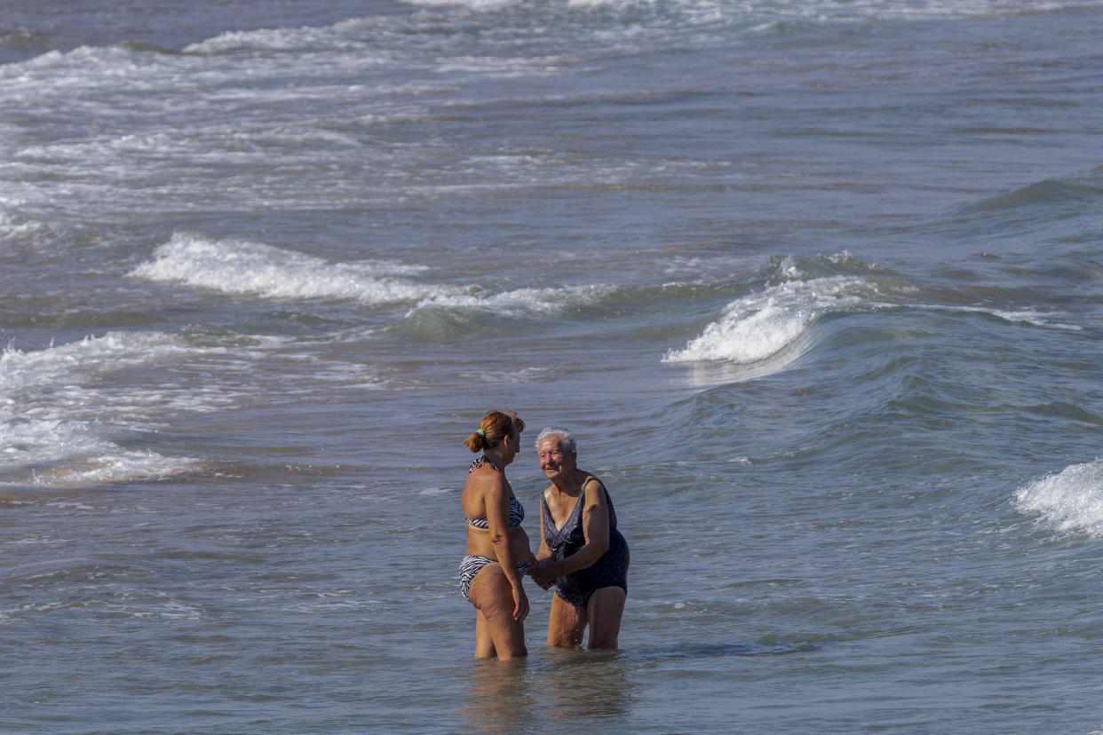 Women cool off on Puerto de Sagunto beach, east Spain on Tuesday, Aug. 16, 2022. While vacationers might enjoy the Mediterranean sea’s summer warmth, climate scientists are warning of dire consequences for its marine life as it burns up in a series of severe heat waves. (AP Photo/Alberto Saiz)