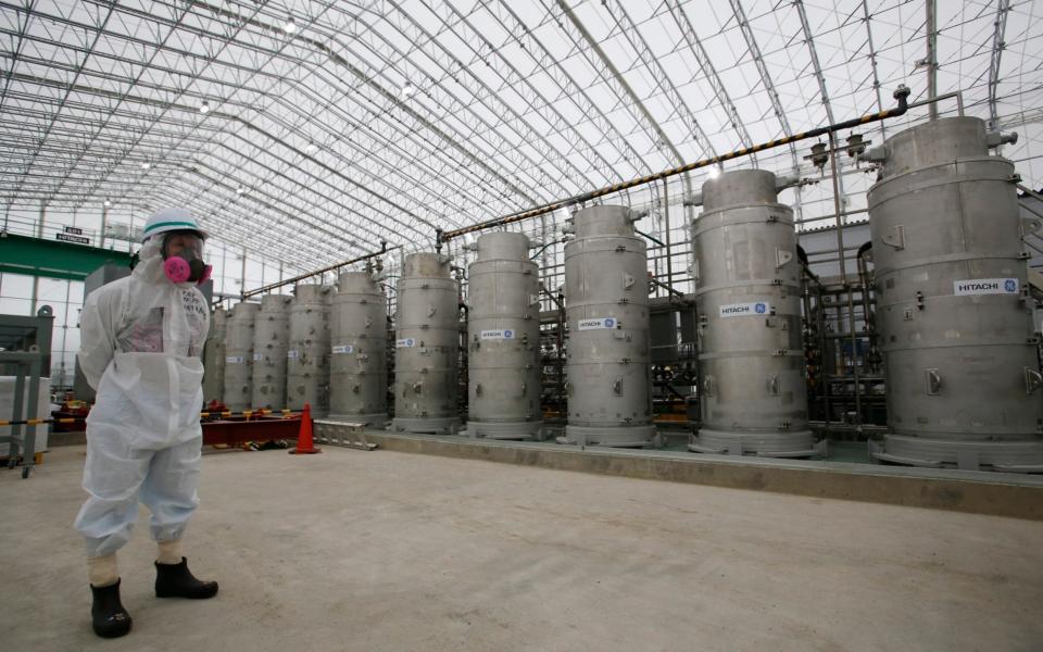 A Tokyo Electric Power Co. (TEPCO) official wearing a radioactive protective gear stands in front of Advanced Liquid Processing Systems during a press tour at the Fukushima Dai-ichi nuclear power plant - AP Pool 