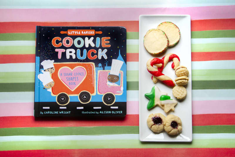 cookie truck cookie plate book next to an assortment of holiday cookies on a plate