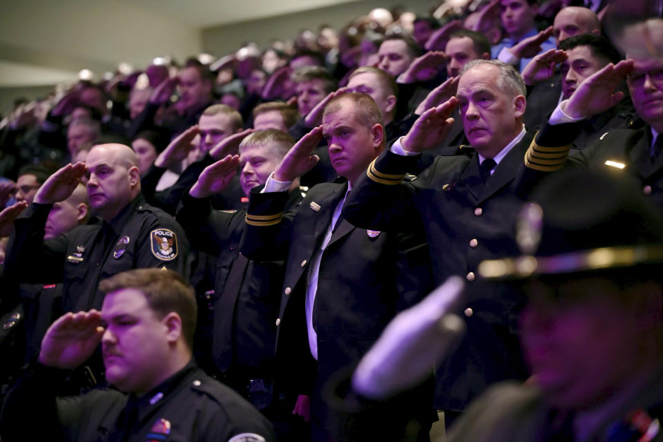 Members of law enforcement salute as the caskets representing the fallen as they are brought into the sanctuary at Grace Church at the start of the memorial service there for Burnsville police officers Paul Elmstrand, 27, Matthew Ruge, 27, and firefighter-paramedic Adam Finseth, 40, in Eden Prairie, Minn., on Wednesday, Feb. 28, 2024. (Aaron Lavinsky/Star Tribune via AP, Pool)