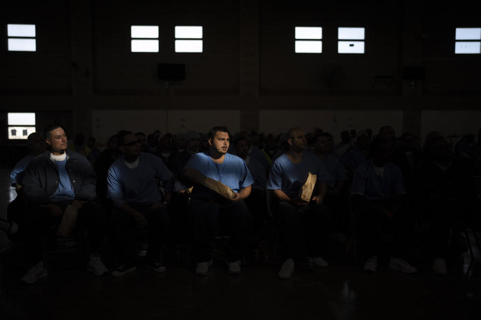 A shaft of light falls on prisoners as they watch a documentary film produced by director Sol Guy in Valley State Prison's gymnasium in Chowchilla, Calif., Friday, Nov. 4, 2022. The gym had been closed for recreational activities like basketball as part of ongoing COVID restrictions. About 150 prisoners were allowed in for the film – individual bags of buttered popcorn and cold beverages included with admission – their excitement palpable after many months of isolation. (AP Photo/Jae C. Hong)