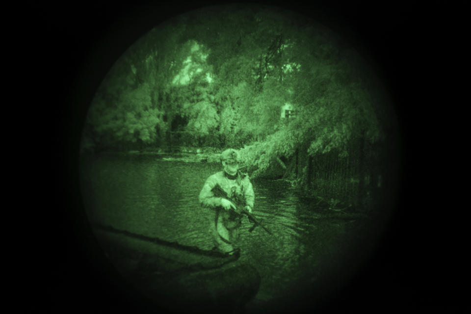 A Ukraine Special Operations Forces soldier walks through water on the shores of the Dnipro River using night vision goggles, or NVG, during a night mission in Kherson region, Ukraine, Sunday, June 11, 2023. They transform themselves from nondescript civilians into elite fighters, some in wetsuits and some in boats. In the morning, when their operations end, they’re back to anonymity. (AP Photo/Felipe Dana)