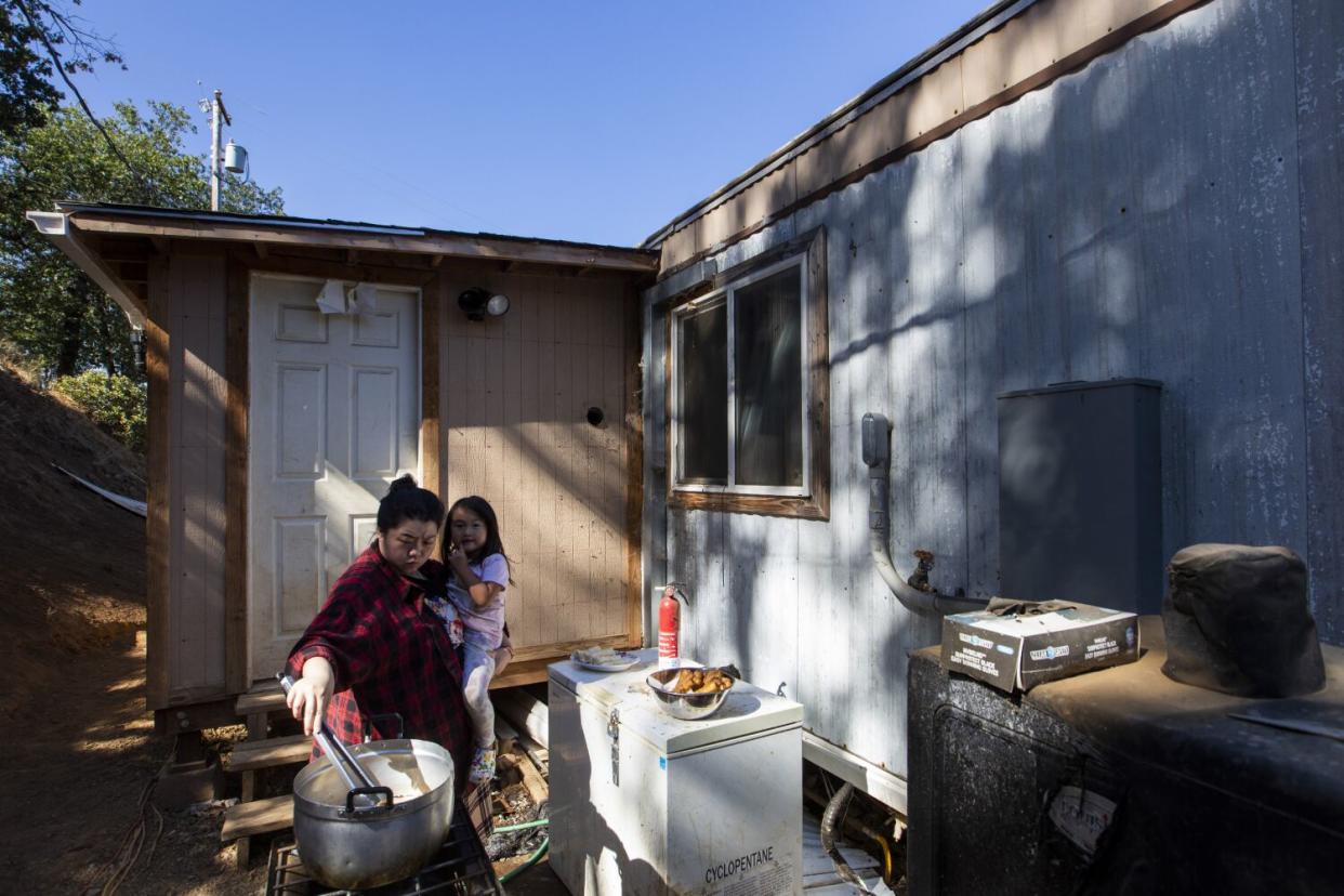 Michelle Vang holds niece Amy Vang, 4, as she cooks egg rolls on an outdoor stove