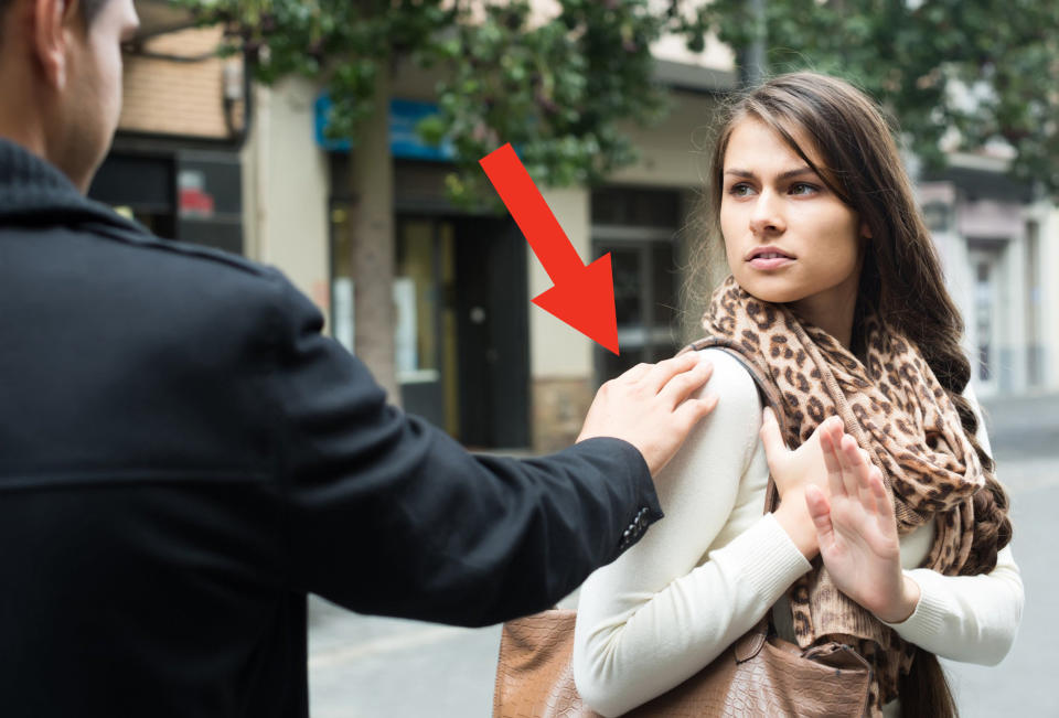 a man tapping a woman on a shoulder as she has her hand up to keep walking