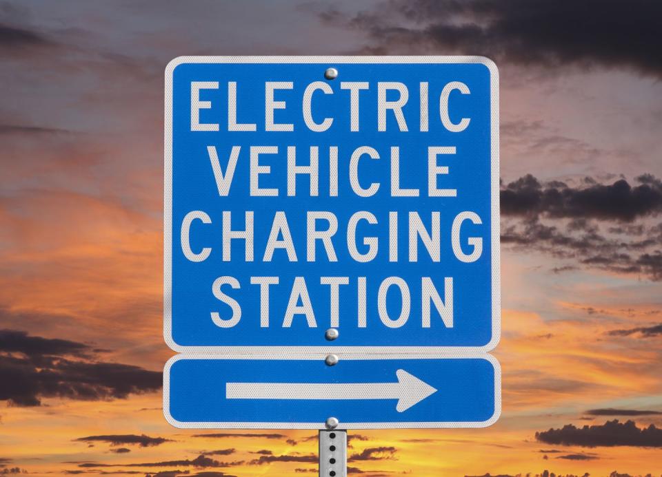 electric vehicle charging station sign with sunset sky