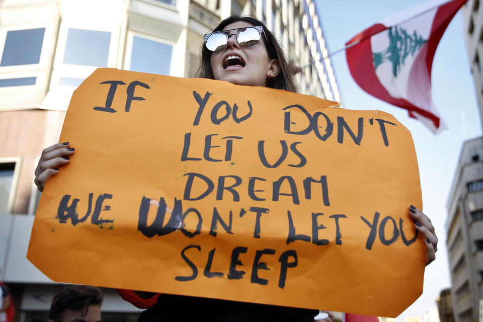 A student protester holds a placard as she chants slogans against the Lebanese government, in Beirut, Lebanon, Tuesday, Nov. 12, 2019. Protesters in Lebanon resumed demonstrations on Tuesday blocking some roads and governmental institutions. (AP Photo/Bilal Hussein)