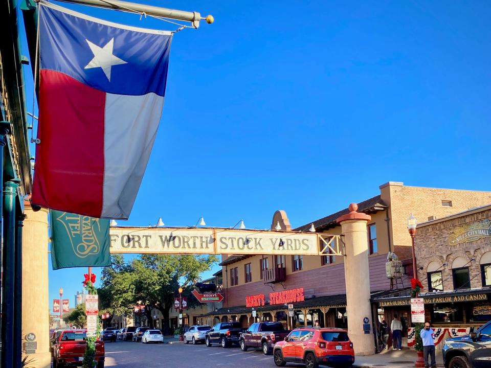 The Texan flag hanging from a shop on a cobblestone street lined with stores.