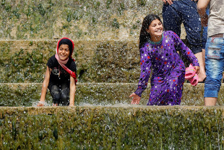 Iraqi girls play with water as they enjoy their Friday holiday with their family at Shallalat district (Arabic for "waterfalls") in eastern Mosul, Iraq, April 21, 2017. REUTERS/ Muhammad Hamed